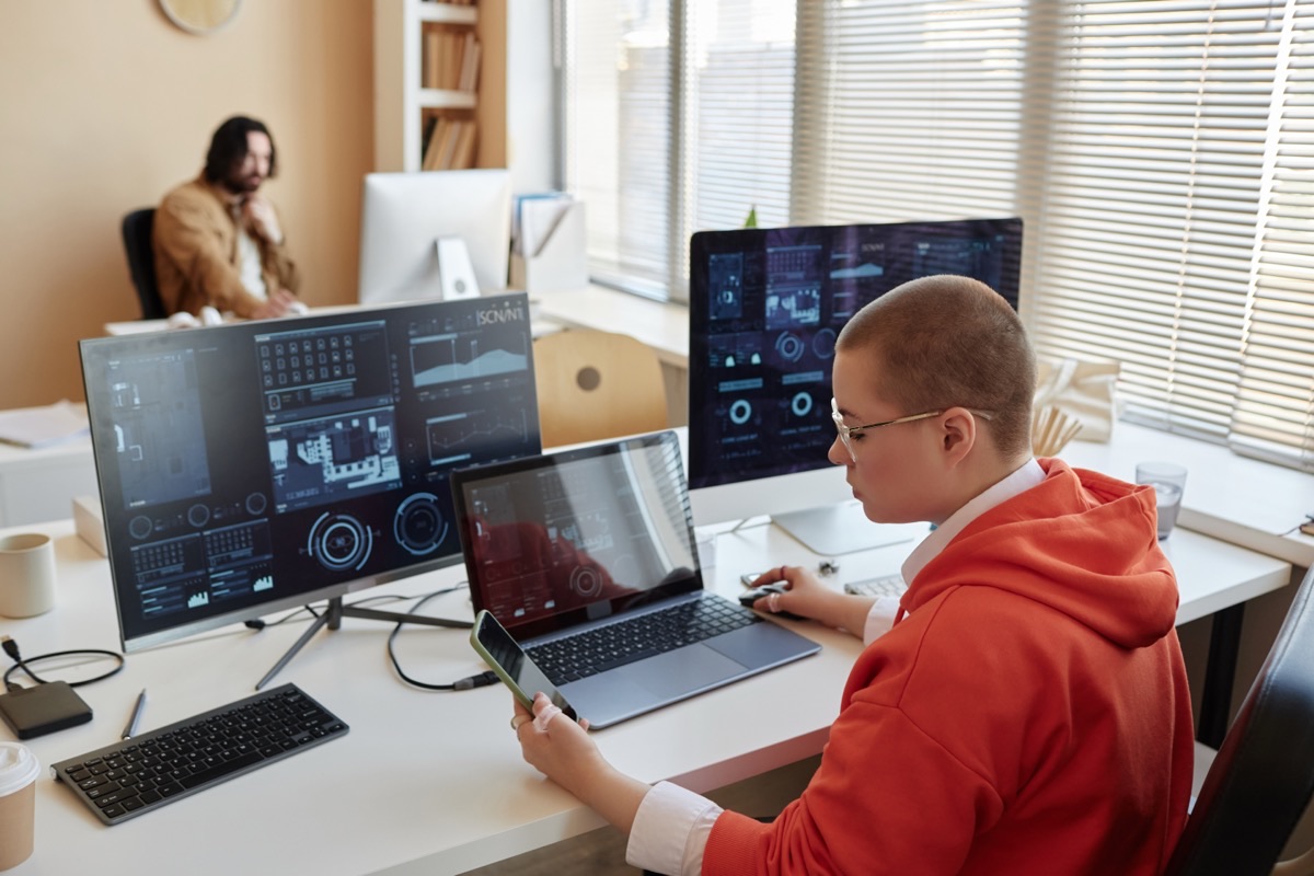 IT-konsult som analyserar säkerhetsdata på flera skärmar